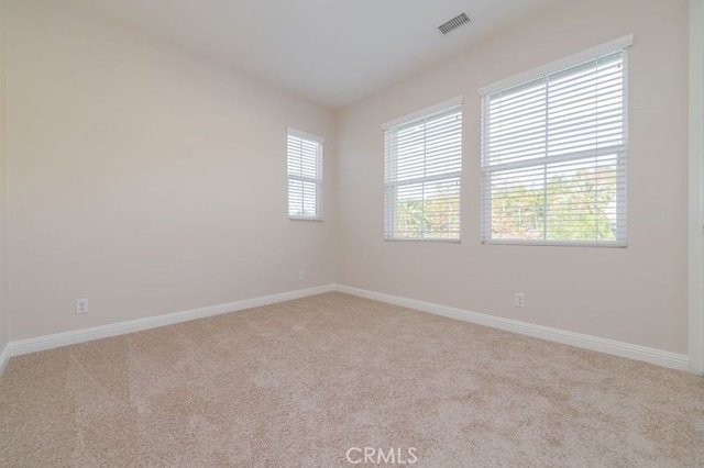 carpeted spare room with baseboards, visible vents, and a wealth of natural light