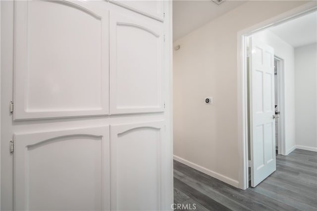 corridor with dark wood-style floors and baseboards