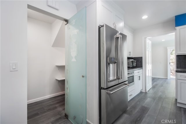 kitchen featuring appliances with stainless steel finishes, dark wood-style flooring, backsplash, and white cabinetry