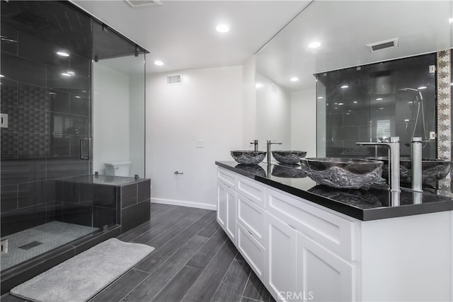 bathroom featuring wood tiled floor, visible vents, a sink, and a shower stall