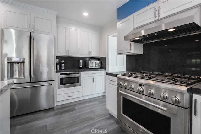 kitchen featuring white cabinets, backsplash, high quality appliances, and under cabinet range hood