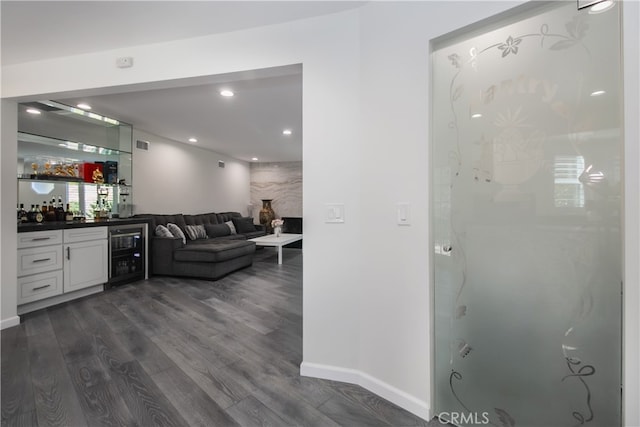 interior space with beverage cooler, visible vents, baseboards, dark wood-style floors, and a bar