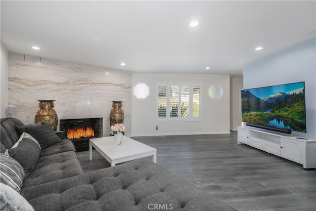 living area with baseboards, wood finished floors, a high end fireplace, and recessed lighting