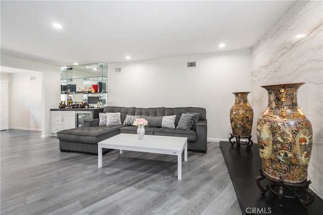 living area with baseboards, visible vents, wood finished floors, a bar, and recessed lighting