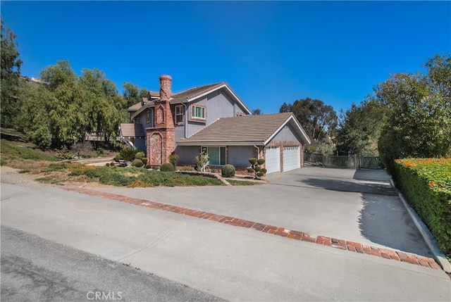 traditional-style home with concrete driveway, fence, a chimney, and an attached garage