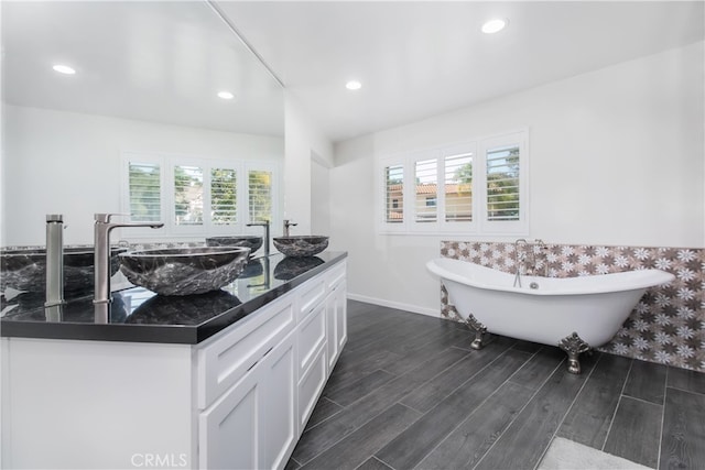 full bathroom with wood tiled floor, a soaking tub, a sink, and recessed lighting