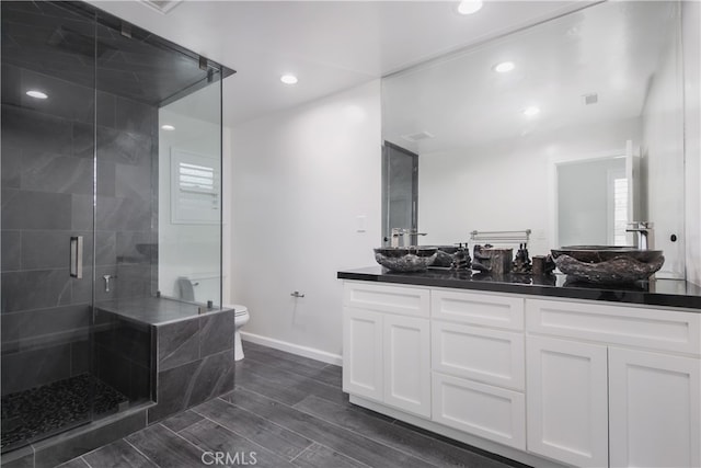 bathroom featuring a stall shower, baseboards, toilet, wood tiled floor, and vanity