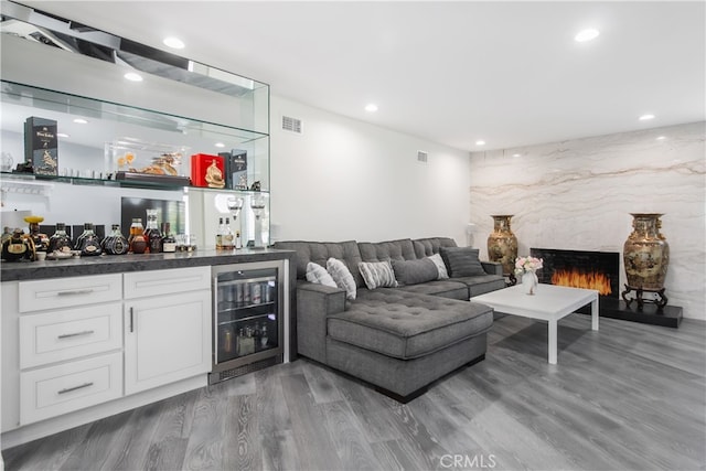 bar with visible vents, wine cooler, a premium fireplace, wood finished floors, and a bar