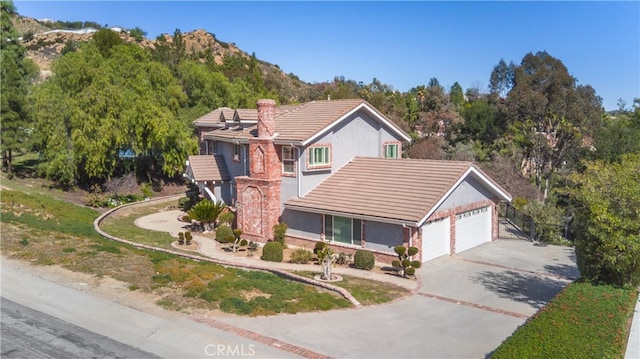 view of front of house featuring brick siding, stucco siding, concrete driveway, an attached garage, and a tiled roof