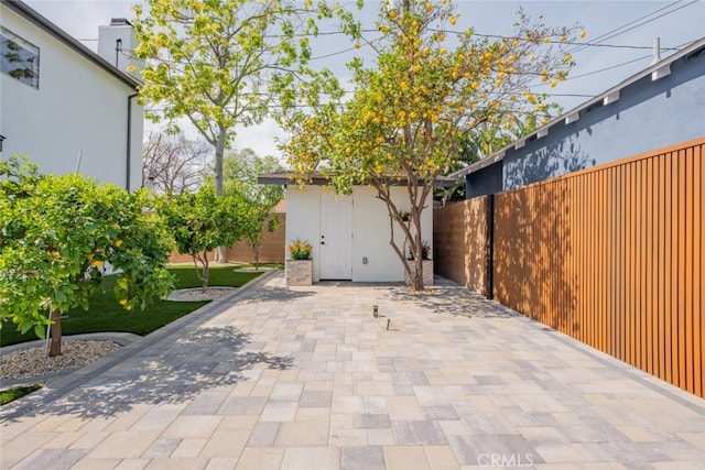 view of patio featuring an outdoor structure, a storage unit, and a fenced backyard