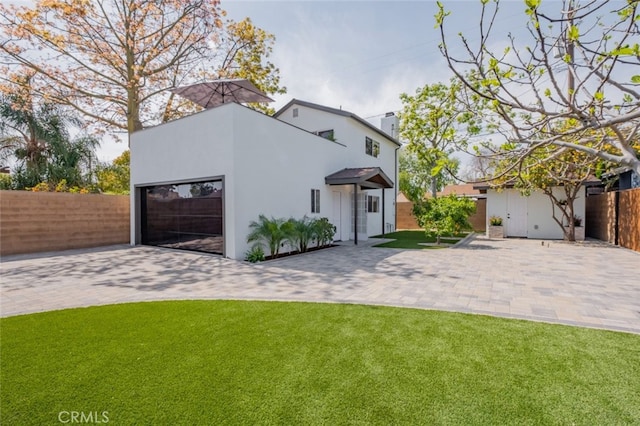 view of front of house with a front lawn, fence, a chimney, decorative driveway, and an attached garage