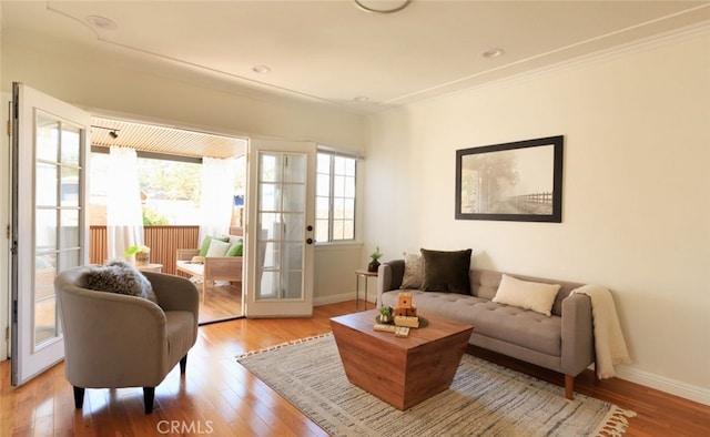 living area featuring wood finished floors, baseboards, french doors, and ornamental molding