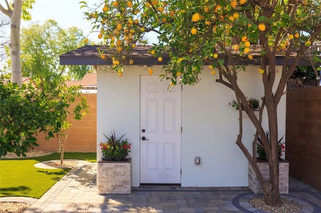 doorway to property featuring stucco siding and fence