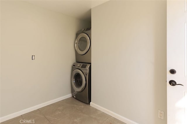 laundry area with laundry area, stacked washer and dryer, and baseboards