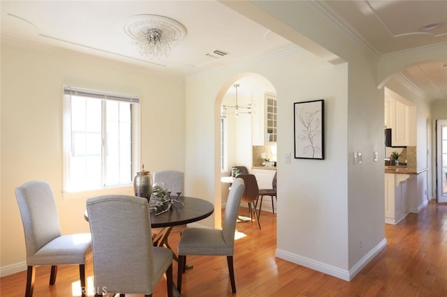 dining space with baseboards, light wood-style flooring, and crown molding