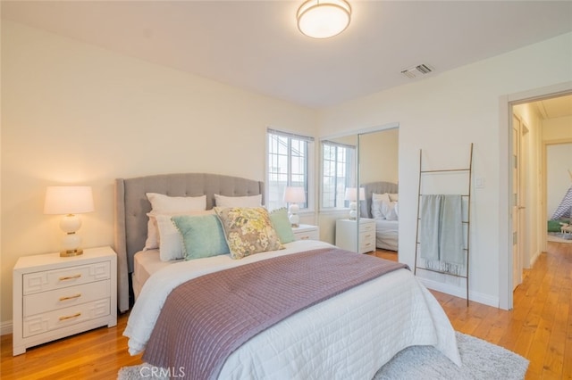 bedroom featuring a closet, visible vents, light wood finished floors, and baseboards