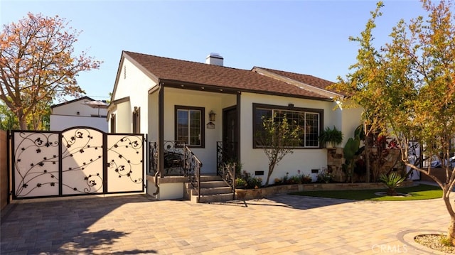 view of front facade featuring crawl space, stucco siding, a chimney, and a gate