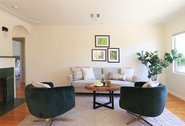 living area with visible vents, arched walkways, wood finished floors, and crown molding