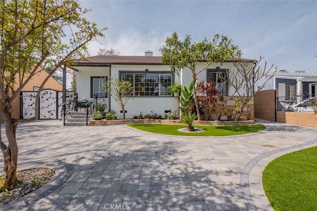 view of front of house with stucco siding, fence, and a gate