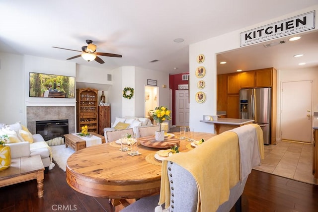 dining space featuring recessed lighting, light wood-style floors, visible vents, a ceiling fan, and a glass covered fireplace