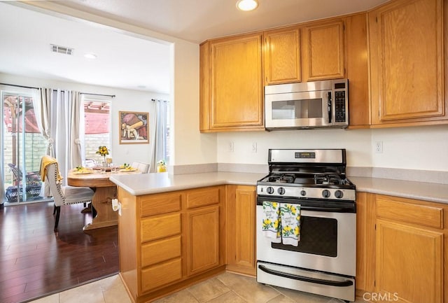 kitchen featuring light countertops, visible vents, a peninsula, recessed lighting, and appliances with stainless steel finishes