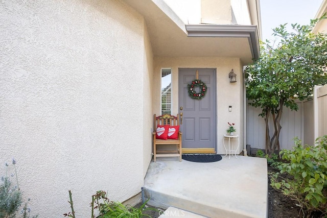 property entrance featuring stucco siding and fence
