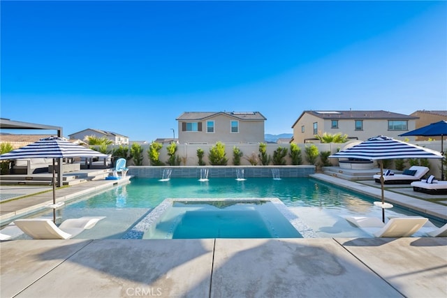 view of swimming pool with a fenced backyard, a pool with connected hot tub, and a patio