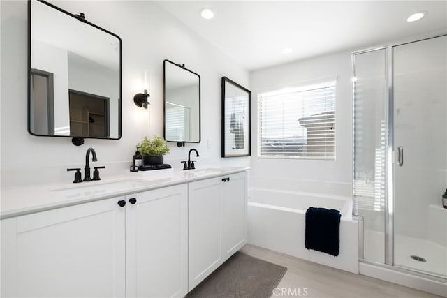 bathroom with double vanity, a sink, a bath, and a shower stall