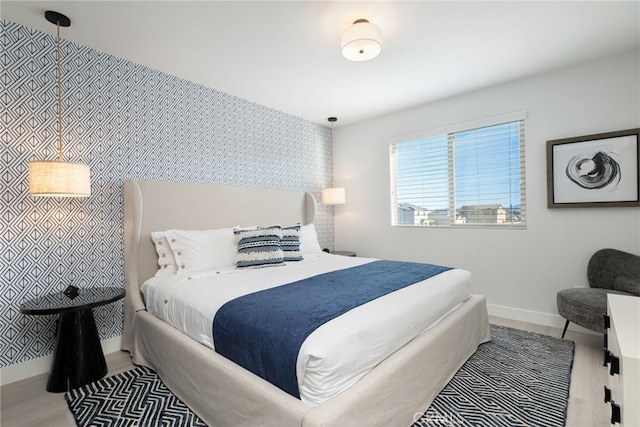 bedroom with an accent wall, baseboards, and wallpapered walls