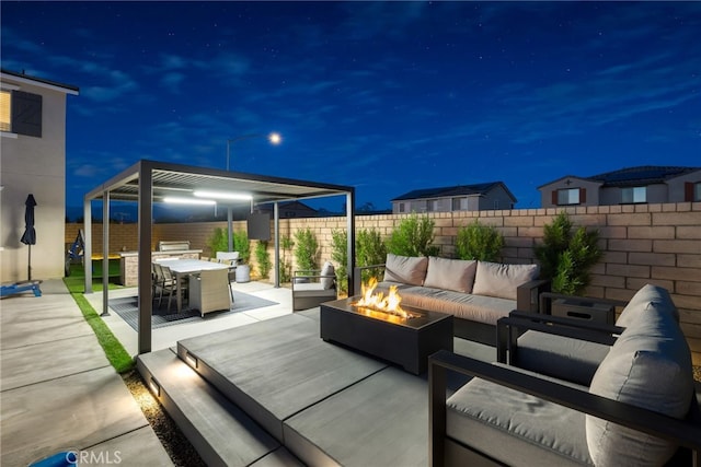 patio at night with outdoor dining space, a fenced backyard, and an outdoor living space with a fire pit