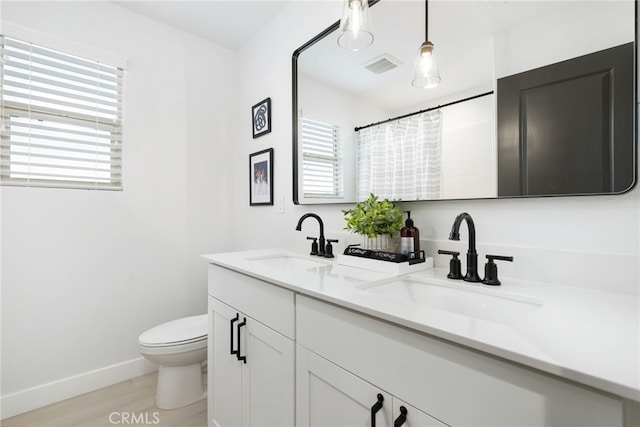 bathroom with toilet, visible vents, a sink, and wood finished floors