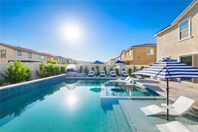 view of swimming pool featuring a fenced backyard, a residential view, a pool with connected hot tub, and a patio