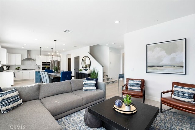 living area with a notable chandelier, recessed lighting, visible vents, light wood-style floors, and stairway