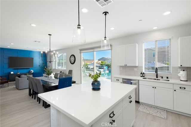 kitchen featuring light countertops, visible vents, decorative backsplash, open floor plan, and a sink