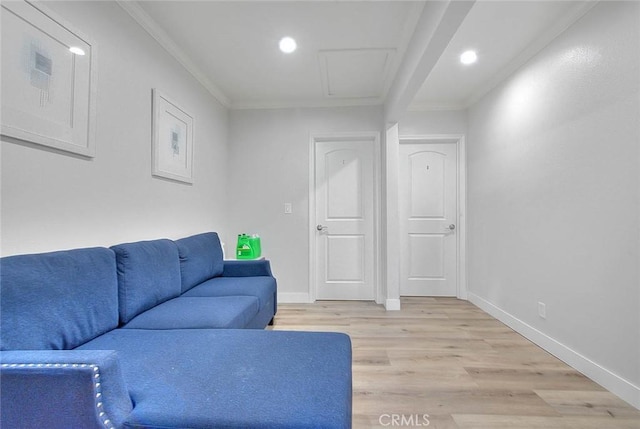 living area with baseboards, light wood finished floors, attic access, and crown molding