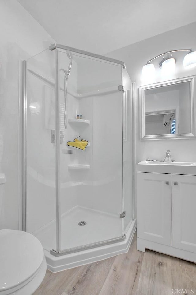 full bathroom featuring vanity, wood finished floors, a shower stall, and toilet