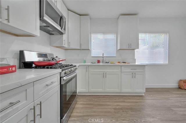 kitchen featuring appliances with stainless steel finishes, a sink, and white cabinetry