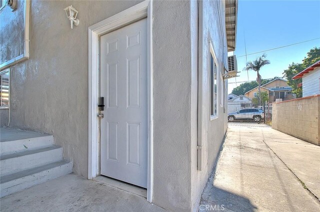 property entrance featuring fence and stucco siding