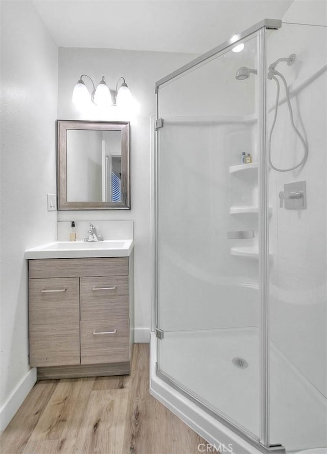 full bathroom with a shower stall, vanity, and wood finished floors