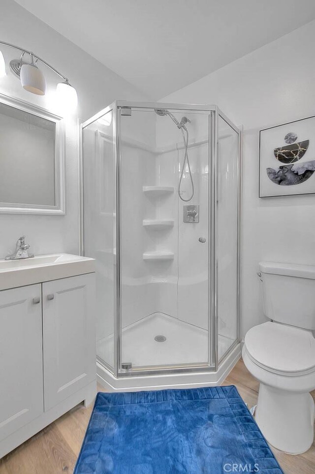 full bathroom with wood finished floors, a shower stall, and toilet