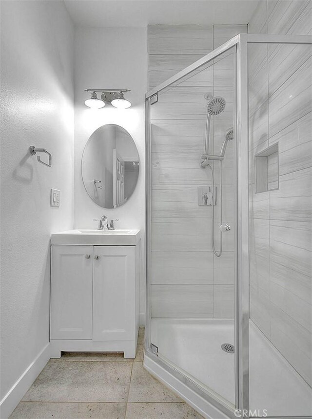 bathroom featuring a stall shower, baseboards, and vanity