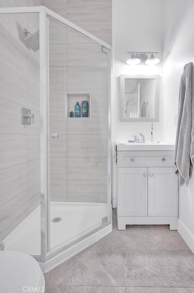 bathroom featuring toilet, a shower stall, and vanity