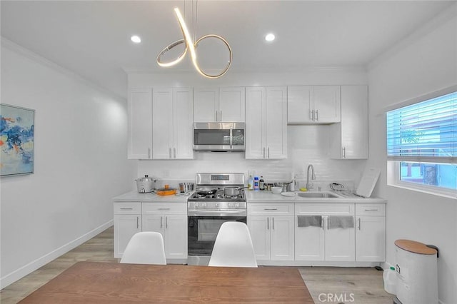 kitchen with white cabinetry, stainless steel appliances, a sink, and light countertops