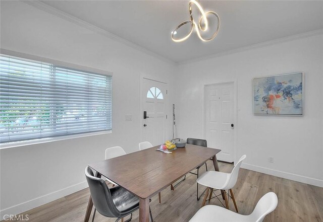 dining room featuring a chandelier, crown molding, light wood-style flooring, and baseboards