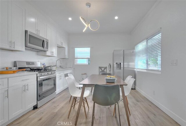 kitchen with stainless steel appliances, a healthy amount of sunlight, white cabinetry, and a sink