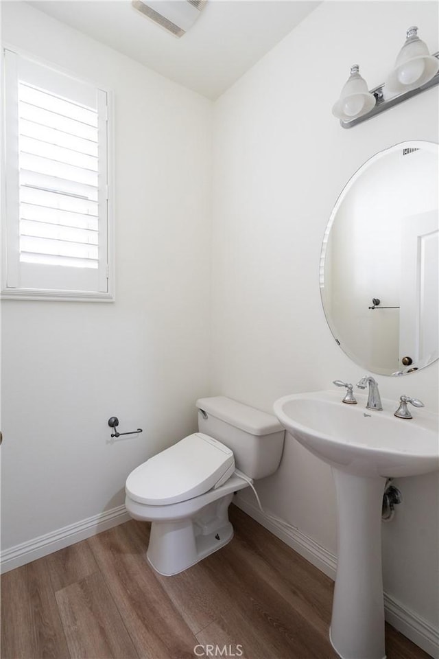 bathroom with toilet, baseboards, and wood finished floors