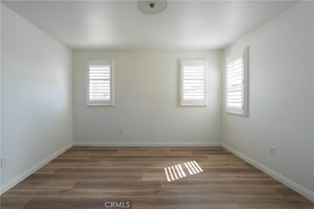 empty room featuring wood finished floors and baseboards