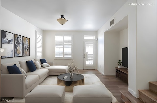 living room with light wood-style flooring, a healthy amount of sunlight, visible vents, and baseboards