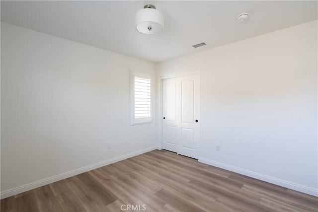 spare room with visible vents, baseboards, and wood finished floors