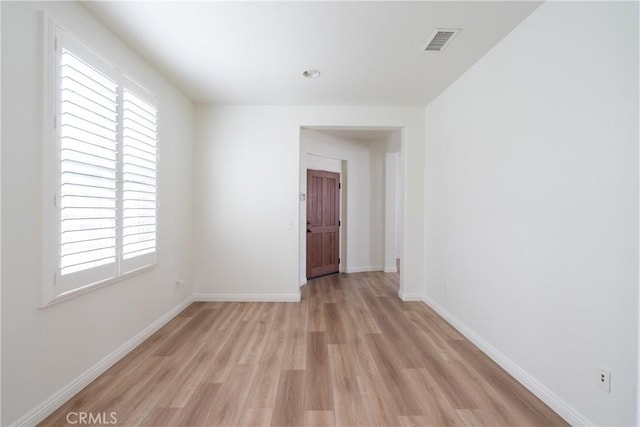 unfurnished room with light wood-type flooring, visible vents, and baseboards